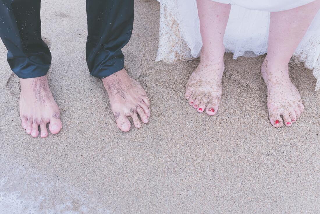 elder man and woman with bare feet in the sand