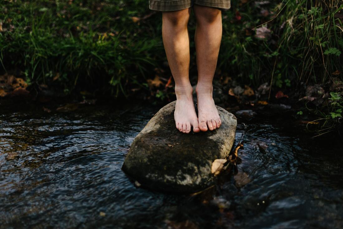 feet standing on a rock barefoot in a river
